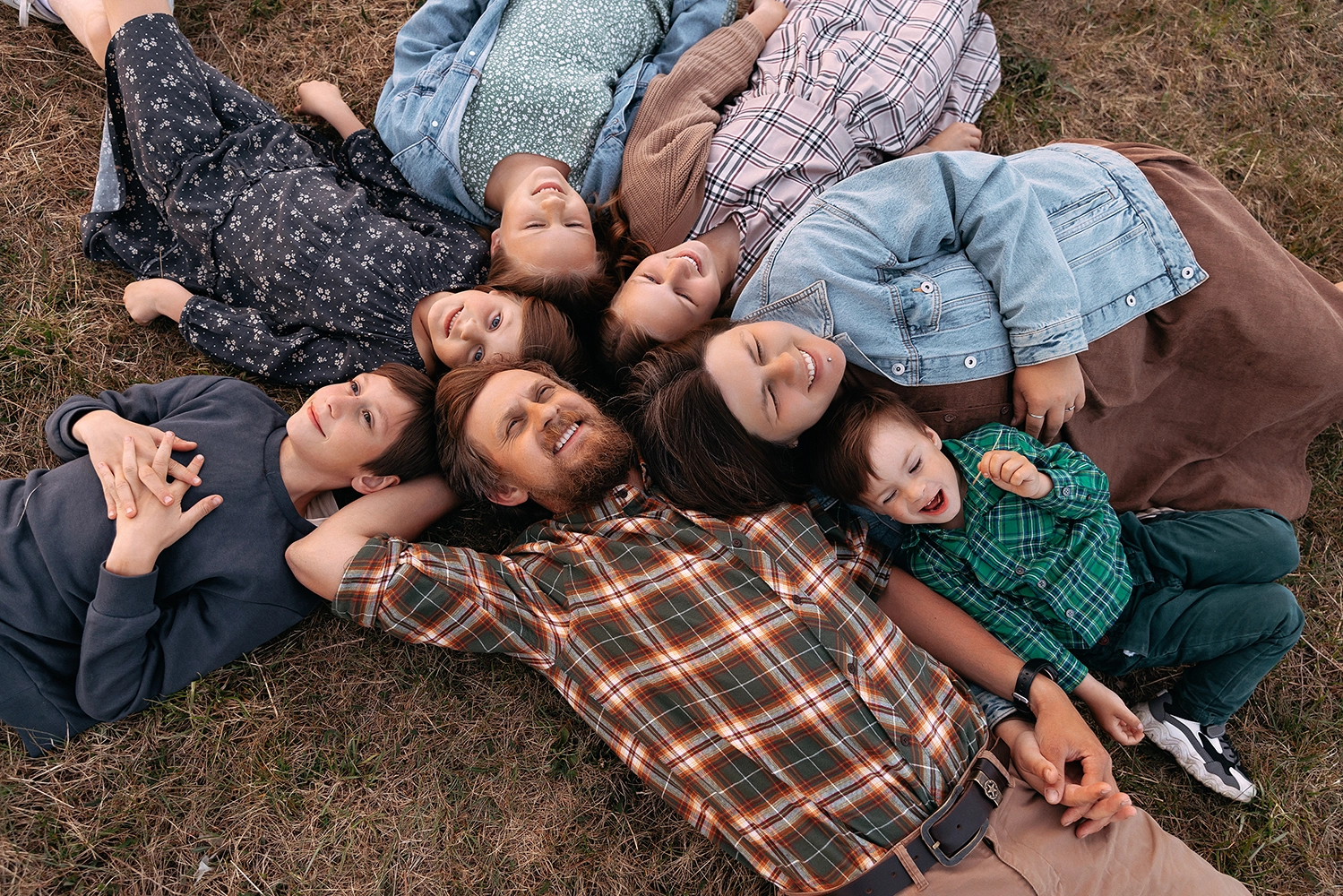 Velká rodina leží v kruhu na trávě